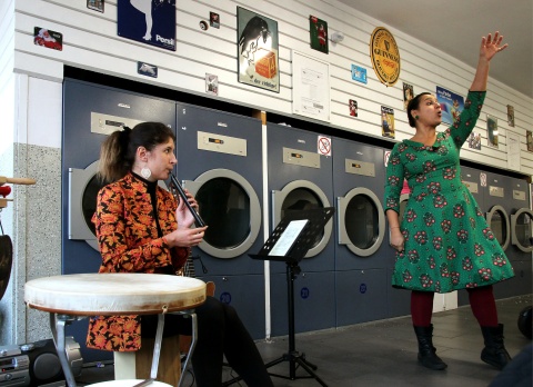 Eine Flötistin und eine Geschichtenerzählerin haben einen Auftritt in einem Waschsalon.
