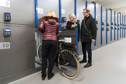 Eine Frau schiebt gerade ihr Fahrrad in eine der Fahrradboxen in dem Fahrradparkhaus am Dom.