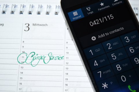 Ein Handy wählt die Nummer des Bürgertelefons
