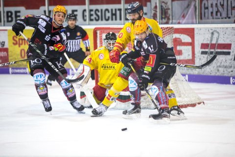 Zwei verschiedene Eishockey Teams duellieren sich vor dem Tor. 