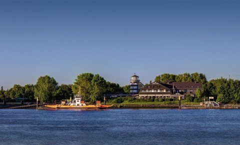 Ein Blick von der anderen Weserseite auf das Ringhotel Fährhaus Farge. Links befindet sich auch ein Schiff.