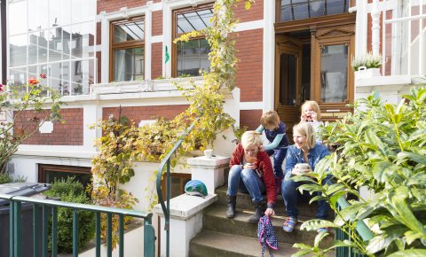 Zwei Frauen und zwei Kinder sitzen auf einer Treppe in einem Hauseingang; Quelle: WFB/Thomas Hellmann