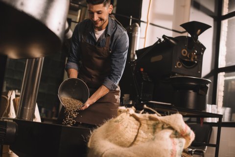 Ein Arbeiter schüttet Kaffeebohnen in eine Maschine