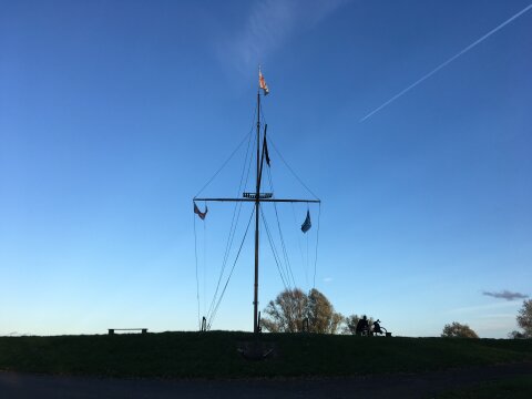 Ein Bauwerk, das an die Segel eines Bootes erinnert, vor blauem Himmel und auf einem Deich