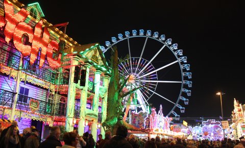 Bunt beleuchtete Buden und Fahrgeschäfte auf dem Bremer Freimarkt bei Nacht.