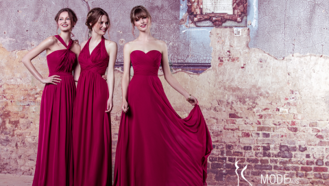 Drei Models stehen in roten Kleidern vor einer Wand.