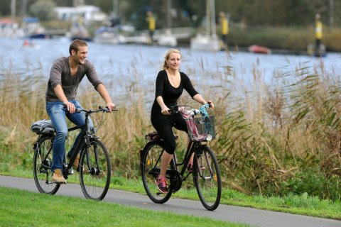 Ein Mann und eine Frau fahren Rad an der Weser; Foto: WFB Wirtschaftsförderung Bremen GmbH / Ingo Wagner
