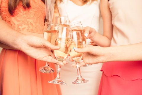 Fünf Frauen stoßen mit einem Glas Sekt an