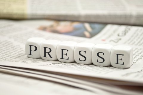 Auf einer Zeitung liegen Buchstaben-Würfel die das Wort "Presse" bilden. 