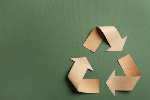 Das Recyclingsymbol vor grünem Hintergrund.