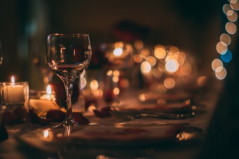 Ein romantisch eingedeckter Tisch mit polierten Gläsern, Kerzenschein und Rosenblättern
