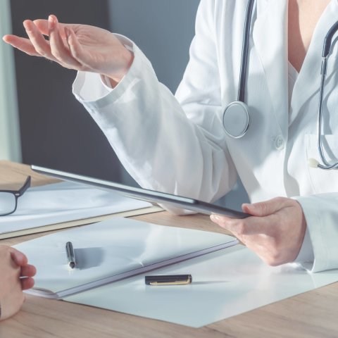 Eine Ärztin erklärt einem Patienten eine Behandlung