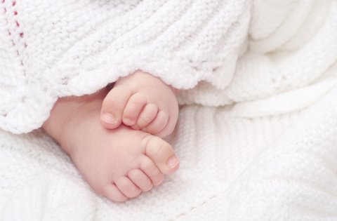 Zu sehen sind Babyfüße, die unter einer Decke hervorgucken.