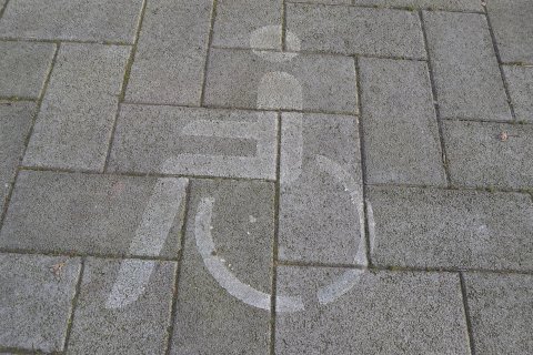 Das Behindertensymbol auf dem Boden eines Behindertenparkplatzes.