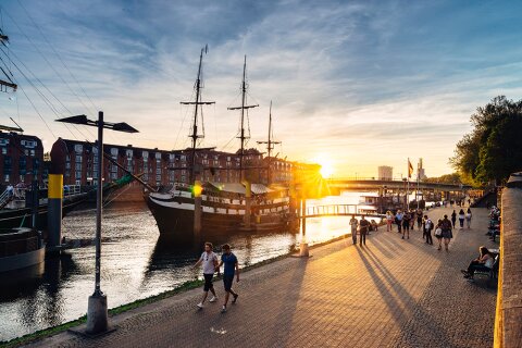 Das Pfannkuchenschiff Admiral Nelson und schlendernde Menschen an der abendlichen Weserpromenade Schlachte