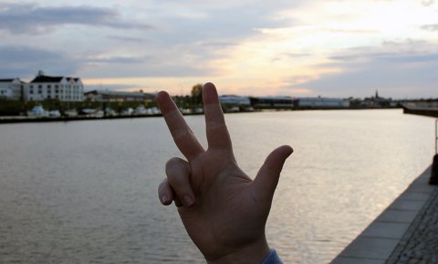 Eine Hand zeigt drei Finger, im Hintergrund die Weser
