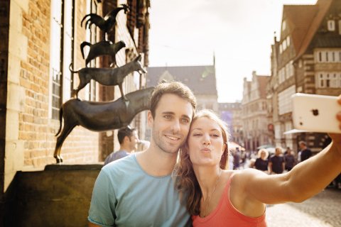 A couple takes a selfie in front of the Bremen Town Musicians.