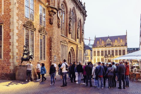 Besucherinnen und Besucher reihnen sich vor den Bremer Stadtmusikanten ein.