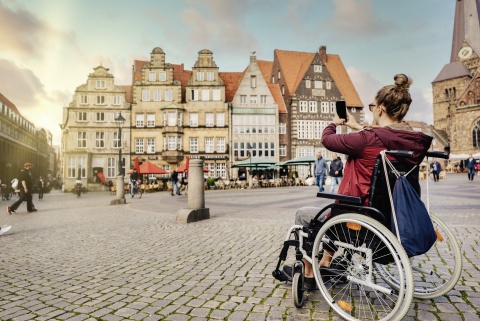 Eine Rollstuhlfahrerin macht Fotos auf dem Marktplatz.