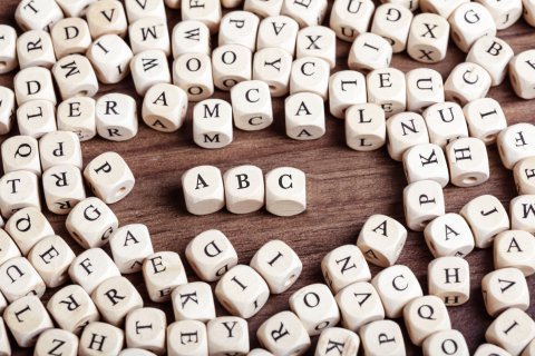 Holzwürfel mit vielen verschiedenen Buchstaben bedruckt, in der Mitte das ABC