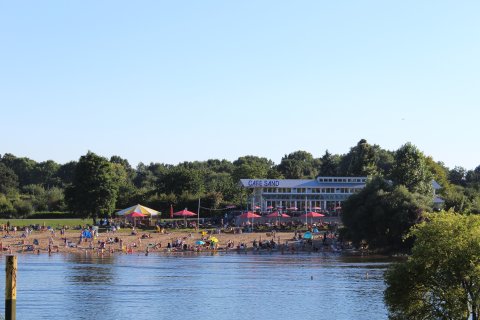 Blick auf Café Sand an einem sommerlichen Tag mit vielen Menschen am Strand.