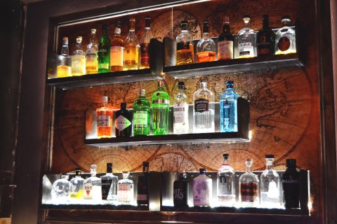 Verschiedene beleuchtete Alkoholsorten auf Regalen an der Wand