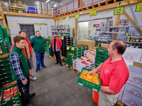 Eine Gruppe von Männern steht im Naturkost Kontor Bremen und nimmt an einer Führung teil. 