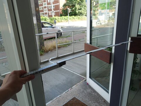 Die Breite einer Eingangstür wird mit einem Zollstock vermessen.