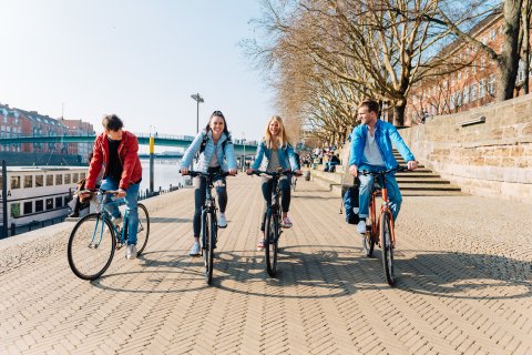 Junge Menschen fahren am Deich Fahrrad