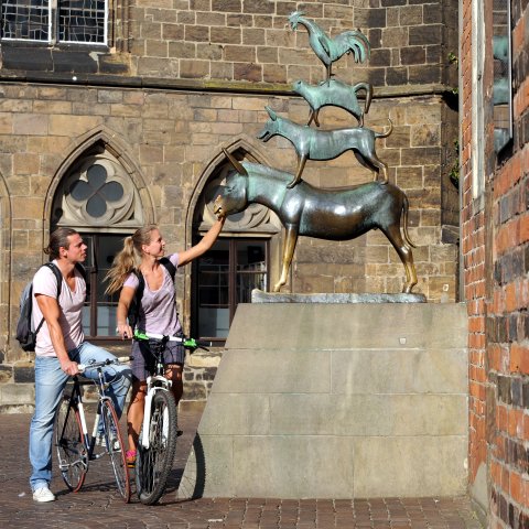 Zwei Fahrradfahrer und die Statue der Bremer Stadtmusikanten
