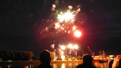 Menschen schauen sich ein Feuerwerk an der Weser an. 