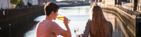 Ein Pärchen sitzt in der Abendsonne auf der Terrasse der Feuerwache in der Überseestadt und blickt auf das Hafenbecken.