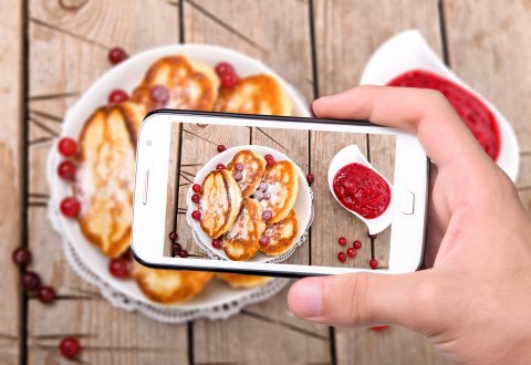Blick durch das Kameradisplay eines Smartphones auf Pfannkuchen mit Früchten