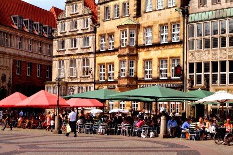 Geschäftiges Treiben bei Sonnenschein auf der Terrasse eines Straßencafés auf dem Bremer Marktplatz.