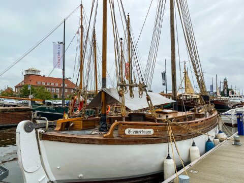 Ein Boot mit dem Namen Bremerhaven liegt in einem Hafenbecken. Im Hintergrund steht ein Gebäude.