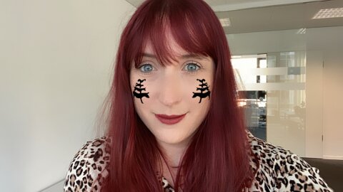 Eine Frau mit roten Haaren hat ein Selfie von sich selbst gemacht. Auf ihren Wangen sind zwei kleine Stadtmusikanten abgebildet. 