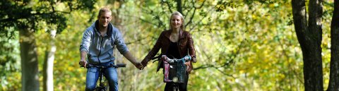 Ein Paar fährt mit dem Fahrrad durch einen Park