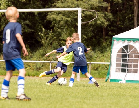 Drei Jungs spielen Fußball auf einem Rasenplatz