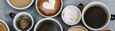 Zahlreiche Becher und Tassen mit unterschiedlichen Kaffeespezialitäten aus der Vogelperspektive