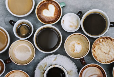 Zahlreiche Becher und Tassen mit unterschiedlichen Kaffeespezialitäten aus der Vogelperspektive