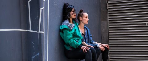 Zwei Künstlerinnen sitzen an einer Wand