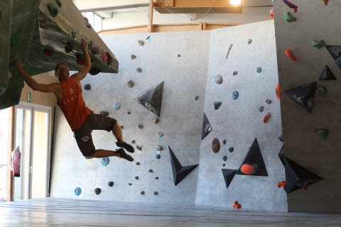 Ein Mann klettert an der Wand entlang.