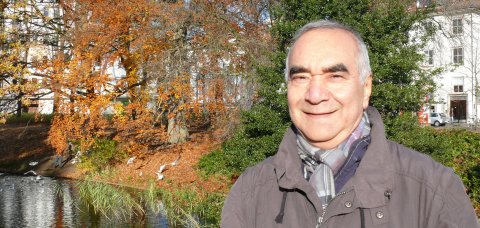 Djafar Khosravi lächelt in die Kamera. Er steht auf einer Grünfläche.