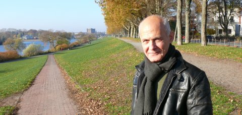 Mehmet Altun lächelt in die Kamera. Er steht auf einer Grünfläche.