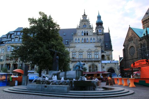Im Hintergrund liegt das historische Gebäude der Bremer Bank. Davor reihen sich einige Marktstände sowie der Neptunbrunnen am Marktplatz.