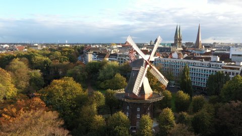 Eine Mühle steht in einem herbstlichen Park. 