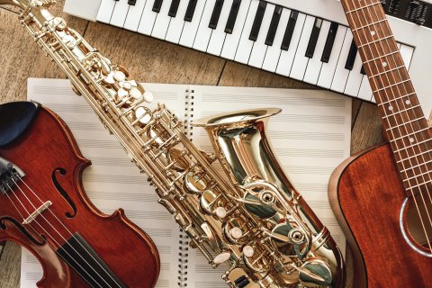 Geige, Saxophon und Gitarre angeschnitten auf Notenpapier liegend