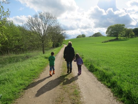 Eine Frau geht mit zwei Kindern auf einem Weg spazieren, links und rechts grüne Wiese und Bäume (Foto: privat/barckhausen).