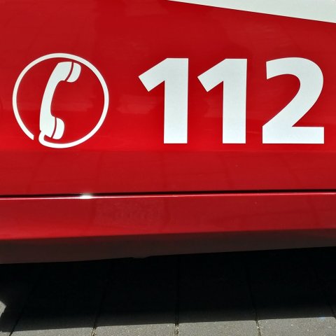 Auf einem roten Fahrzeug befindet sich die Telefonnummer 112