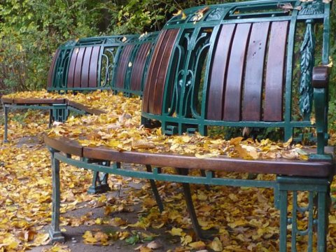 Jugendstil-Parkbank mit Herbstlaub